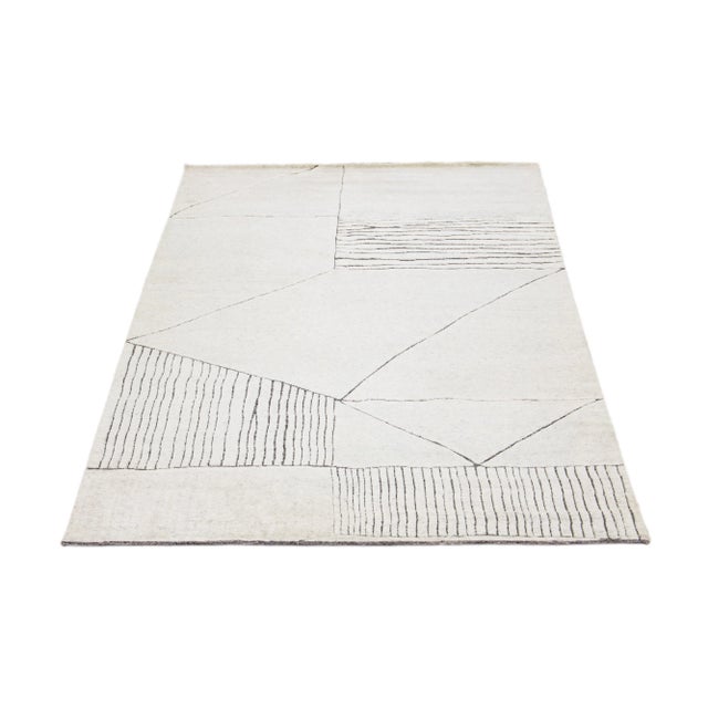 This luxurious wool rug features a timeless Moroccan pattern in a contemporary abstract Minimalist style, utilizing Ivory...