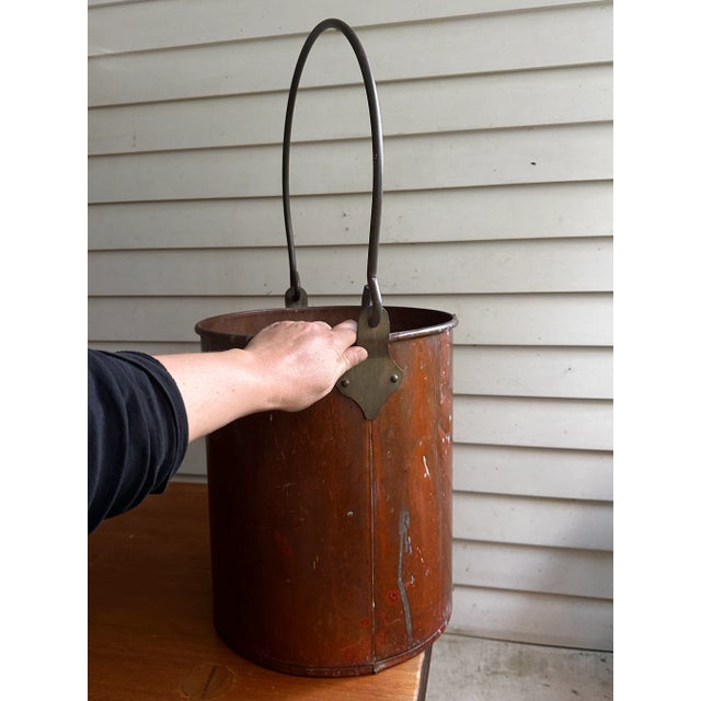 Very large copper bucket with wrought iron handle. 14.5” tall without handle, 27.5” tall with handle, and a diameter of...