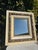 Vintage rectangular mirror featuring a layered wood frame with distressed cream finish and ornate gilt carved detailing....