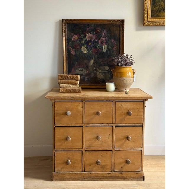 A deep antique pine chest with nine equal drawers in a 3×3 grid, each fitted with a single original turned wooden knob,...