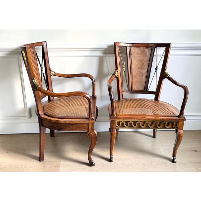 A pair of vintage Regency style mahogany armchairs in a rich wood grain with woven cane seats and backs, decorative...
