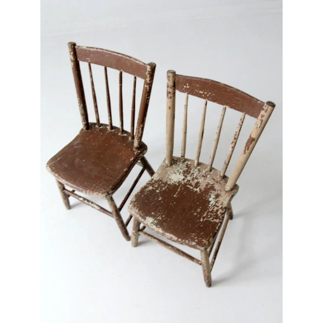 This is a pair of antique American farmhouse chairs. The brown and cream mottled, chippy paint wooden chairs have spindle...