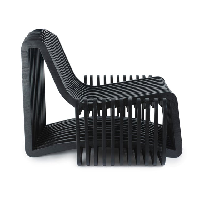 A Mid-Century Modern accent chair in pine wood, defined by sensuous, curving lines and a softly glowing finish that gives...