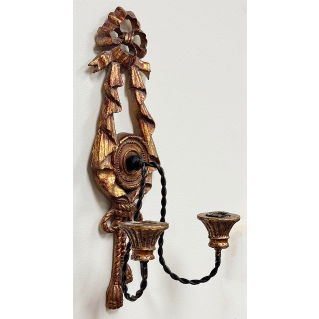 Vintage bronzed gilt wood wall candle sconce featuring ribbon and tassel motif. Two twisted iron arms capped with gilt...