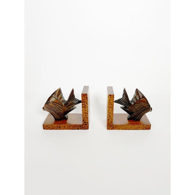 Decorative pair of French bookends from the 1960s featuring finely carved stylized fish mounted on warm-toned wooden...