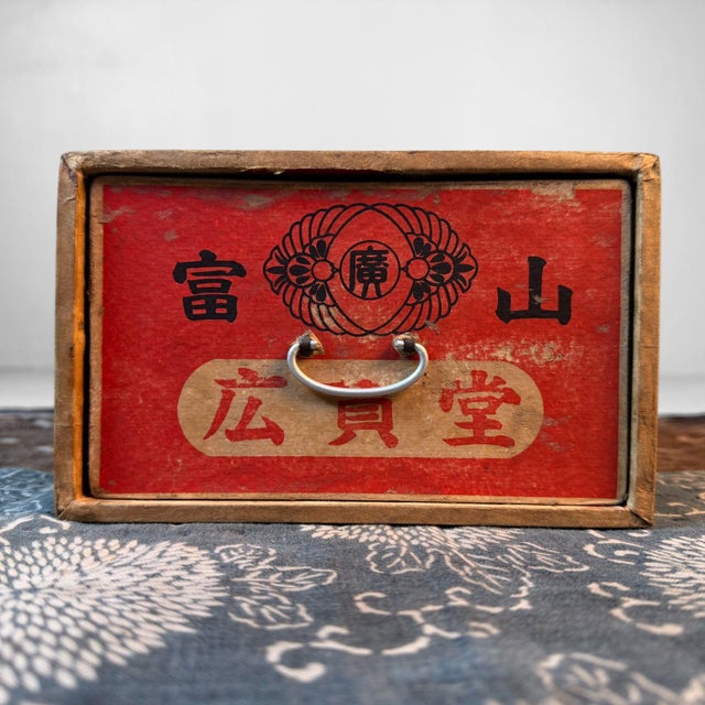 This characterful Japanese box is made from wood covered with paper, with a cardboard drawer and a metal pull handle....