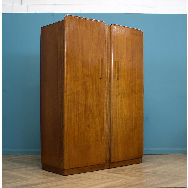 1930s Art Deco wardrobe in walnut veneer with rounded corners, geometric handles and a shaped central detail. from a...