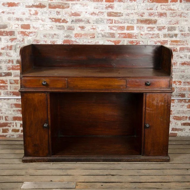Having a flat writing surface galleried in three sides, above two drawers and kneehole flanked by two mahogany panel...