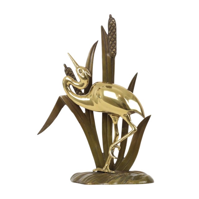 A charming mid-century modern piece: a stylish brass sculpture of a heron set against a background of cattails and reeds...