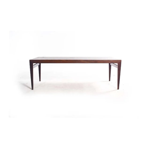 A stunning mid-century rosewood coffee table showcasing the deep, rich grains and hues typical of rosewood from the era....