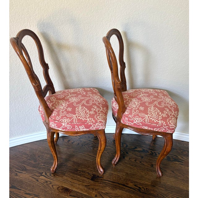 A charming pair of vintage French Provincial side chairs featuring sculptural interlocking ribbon—or “pretzel”—backs and...