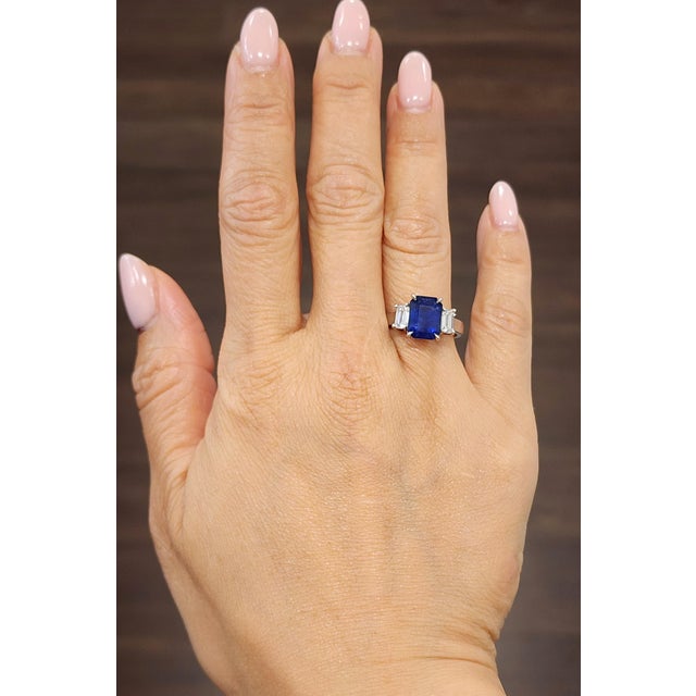 This gorgeous natural sapphire and diamond ring features a 3.77 ct center stone with 2 emeralds on each side weighing 0.72...