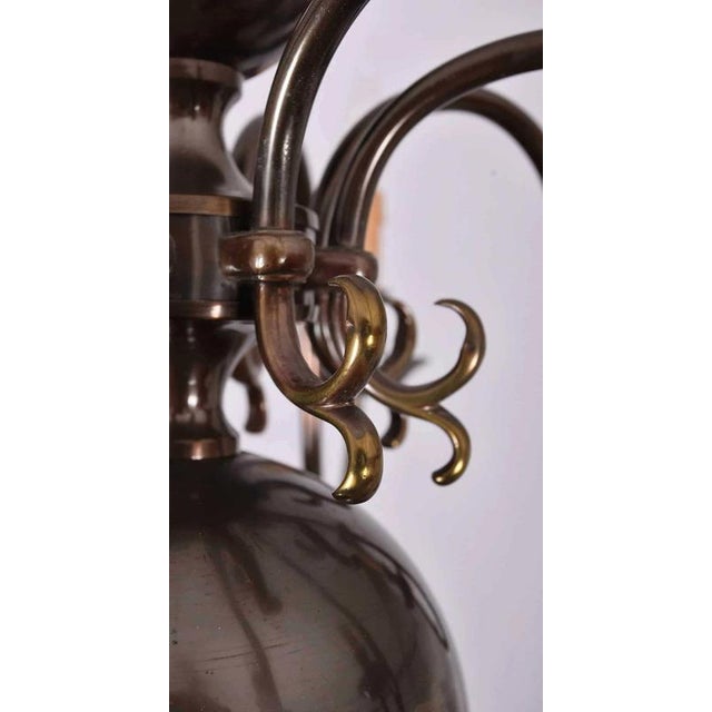 Beautiful eight-armed flemish chandelier made of patinated brass. The upper part of the chandelier is decorated with a...