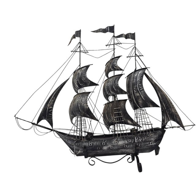 This vintage handcrafted metal ship model is constructed from tinplate, formed sheet metal, and wire rigging, reflecting...