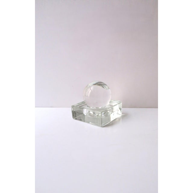 A transparent glass sphere on a square glass base decorative object or paperweight, in the Modern style, circa late-20th...