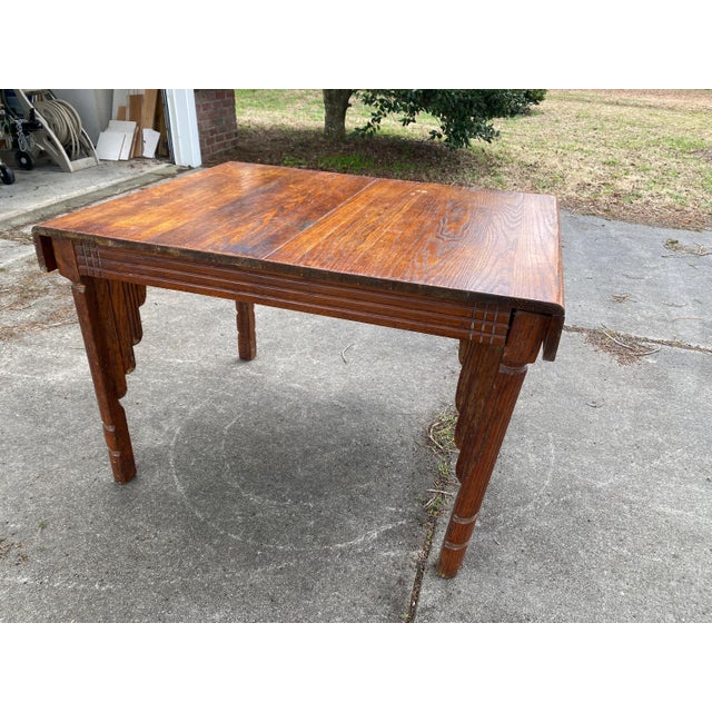 A beautifully crafted early 20th-century oak dining table featuring hand-carved Jacobean Revival detailing and a solid...