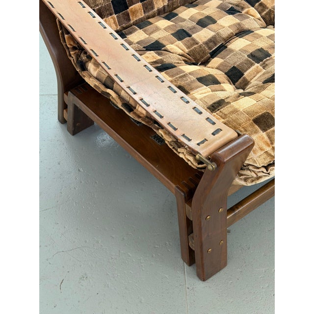 The armchair companion to the checkered sofa, built on the same sculpted solid wood frame with lighter-toned leather arm...