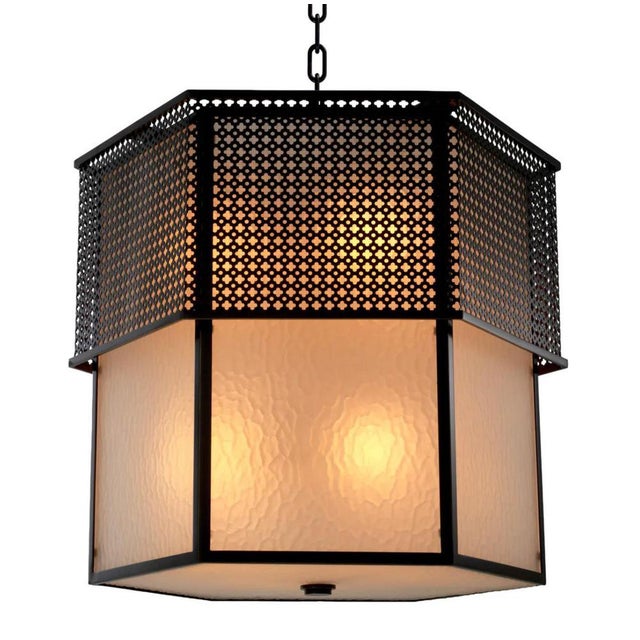Chandelier in metal with a bronze finish and frosted glass. This model features a hexagonal structure composed of tiered...