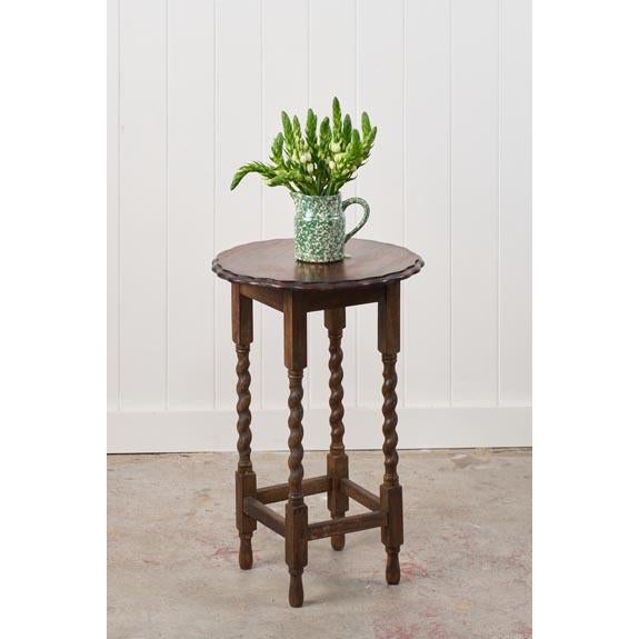 This antique English round oak side table features a circular top with a scalloped edge and barley twist legs connected by...
