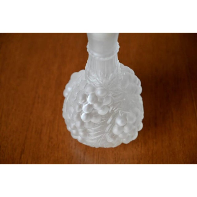 In molded pressed glass with a sandblasted appearance, this carafe is decorated with generous bunches of grapes in relief....