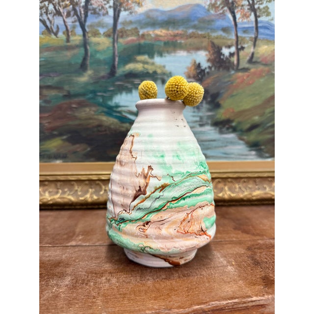 The ceramic pottery is a beautifully crafted vase with a rounded body and a narrow neck. It features a textured surface...
