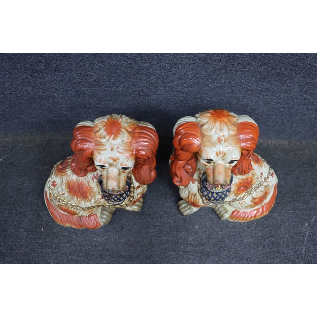 Pair of decorative spaniel dog figurines in the Staffordshire style, each holding a small basket in the mouth. Painted in...