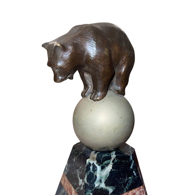 A striking French Art Deco bronze sculpture depicting a bear poised atop a sphere, masterfully capturing both balance and...