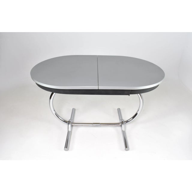 A French mid-century modern extendable kitchen dining table from the 1960s, with an oval Formica top and slender chrome-...