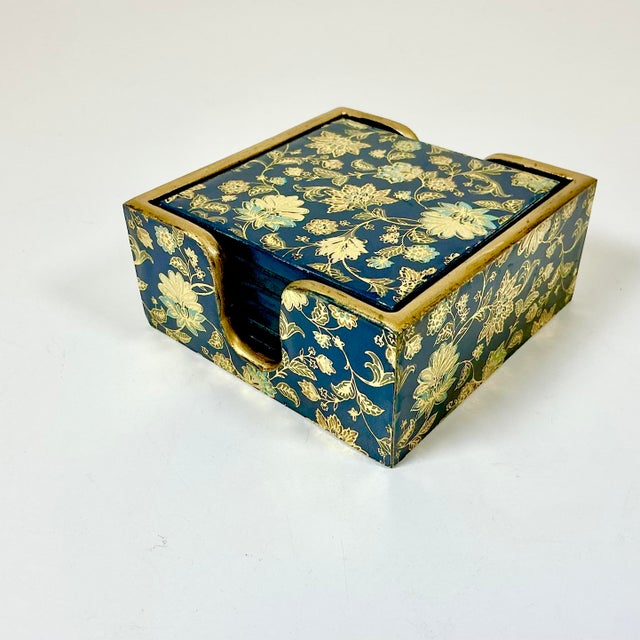 A lovely Chinoiserie Hollywood Regency Set of 6 Coasters with a matching caddy. The design is flora with a brass-colored...