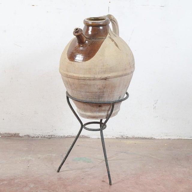 This charming terracotta amphora, complete with its original metal base, is a piece of rustic antiques that evokes the...