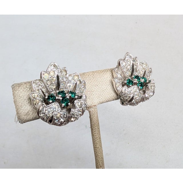 1950s rhodium plated pavé round clear rhinetones and round faux-sapphires flower clip earrings. Marked "JOMAZ" on the...