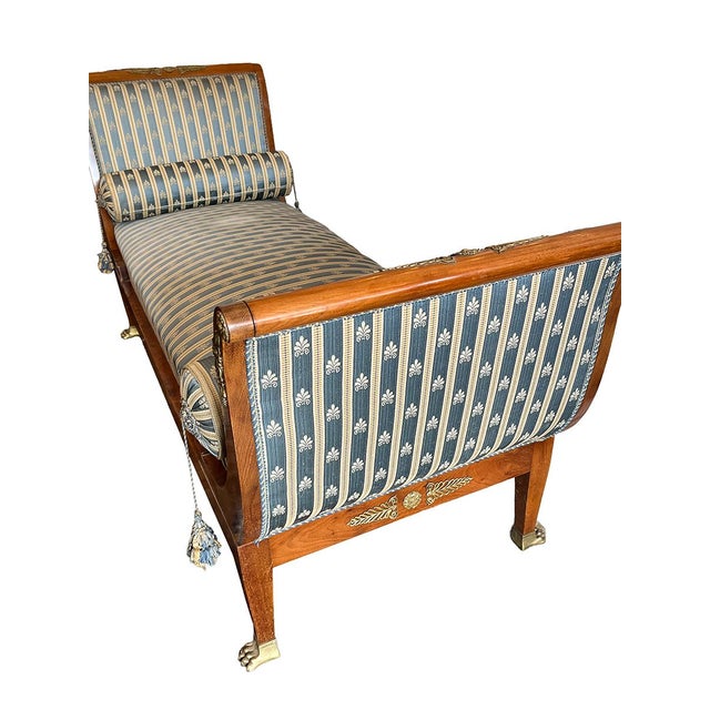 This 19th Century French, Empire-style chaise lounge features a scrolled headrest and bronze chiseled accents and sabre...