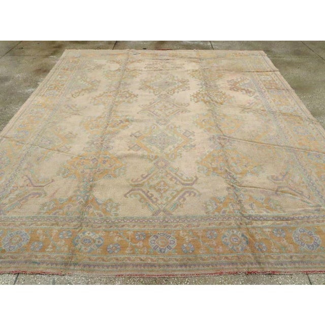 An antique Turkish Oushak room size carpet. Several versions of the foliate lozenge design (Yaprak) are arranged in three...