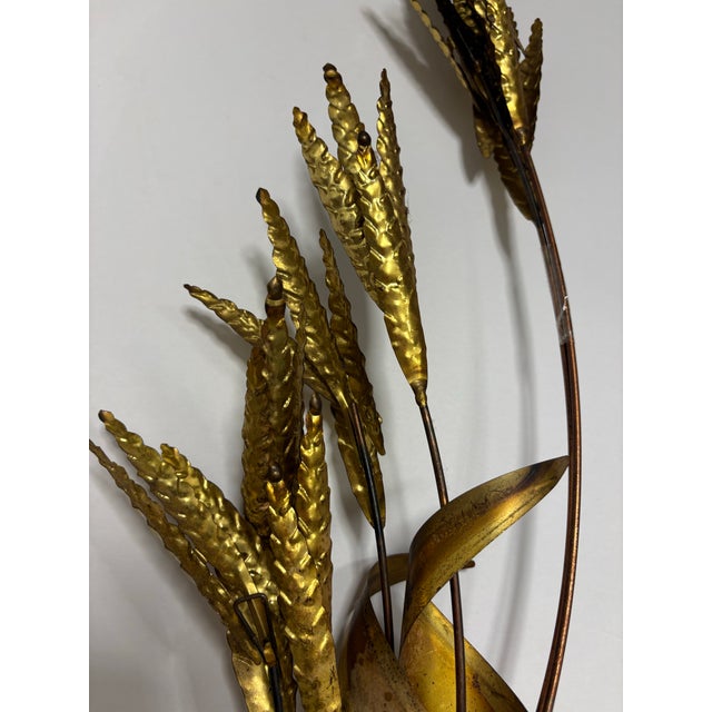 A striking vintage metal wall sculpture featuring a sculptural wheat/botanical spray design. Crafted with hammered brass...