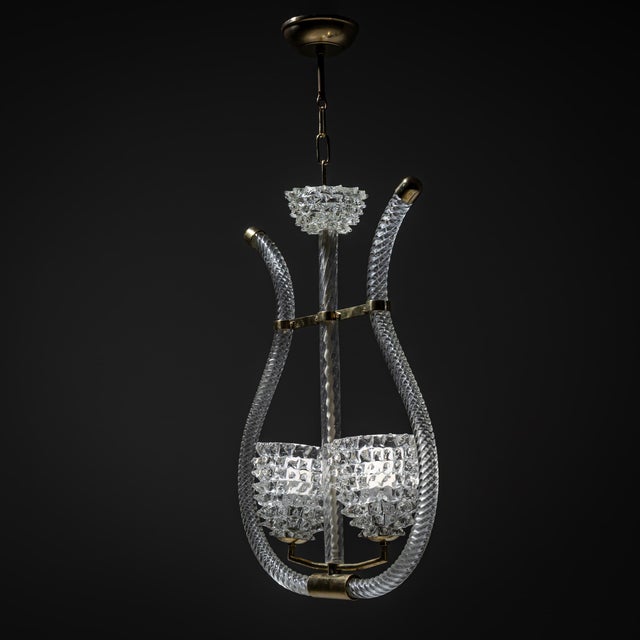 Large lyre-shaped pendant light in clear Murano glass with brass mounts. The fixture features two chalice-shaped shades...