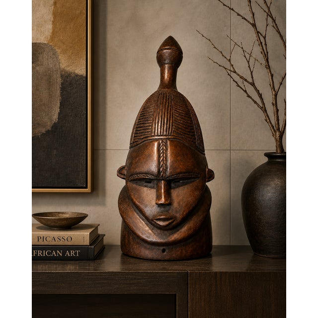 A striking hand-carved West African helmet mask in the Senufo tradition, this sculptural hardwood piece immediately...