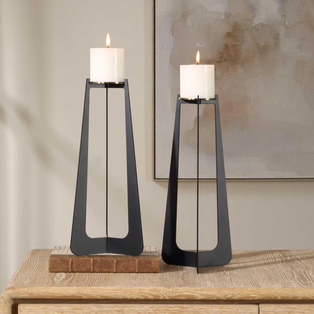 This Striking Pair Of Candle Holders Features A Modern Base Crafted From Iron In A Matte Black Finish With Subtle Antique...