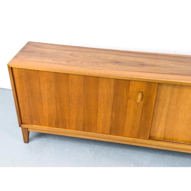 Stunning walnut sideboard with two sliding doors featuring oval recessed handles. Inside, two compartments each have an...