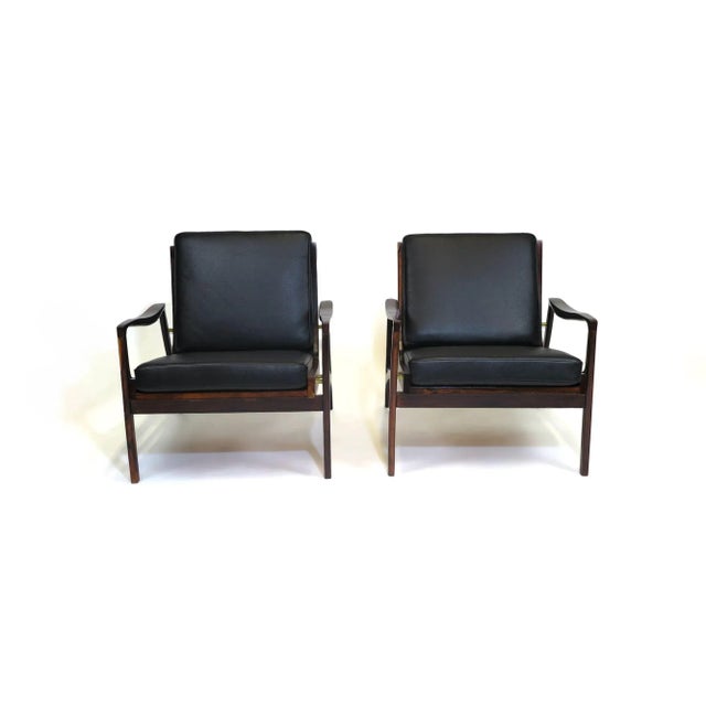 Liceu de Artes e Officios lounge chairs handcrafted from solid Jacaranda in a sculptural form with sloping arms and...