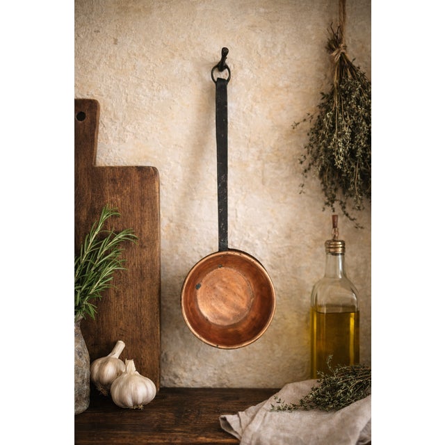 A charming vintage 8" copper sauce pot featuring a warm, time-earned patina and a long hand-forged iron handle with...