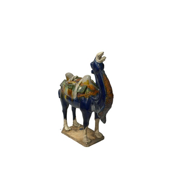 This captivating ceramic sculpture depicts a Bactrian camel rendered in rich sancai-style glazes, capturing the spirit of...