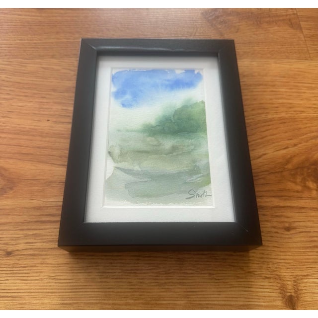 Original watercolor with an atmospheric, minimalist landscape composition. Layers of soft greens and blues suggest mist-...