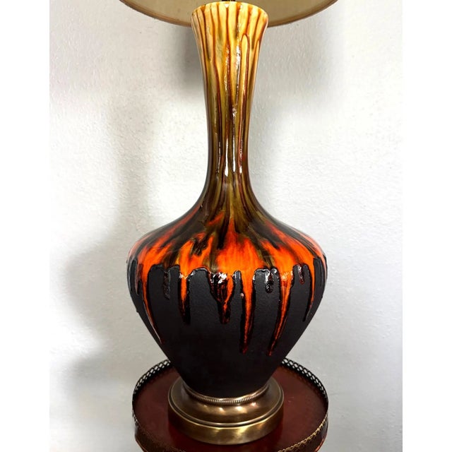 This large 1960s ceramic table lamp features a dramatic lava drip glaze in saturated orange over matte charcoal. The glaze...