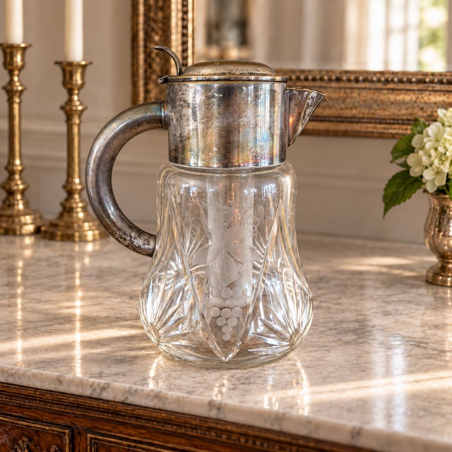 A substantial vintage cut-crystal beverage pitcher with silverplate fittings and its original removable glass cooling...