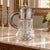 A substantial vintage cut-crystal beverage pitcher with silverplate fittings and its original removable glass cooling...