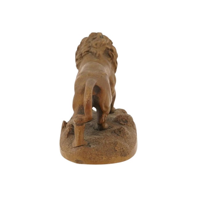 An antique cast bronze sculpture depicting a striding male lion in a dynamic, naturalistic pose with an open maw and a...