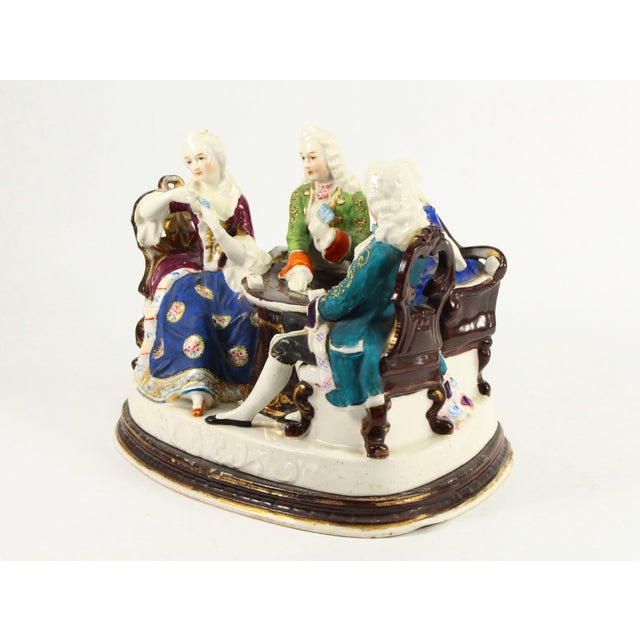 An interesting porcelain inkwell set with sander Designed as a figural group it features a very detailed scene of two...