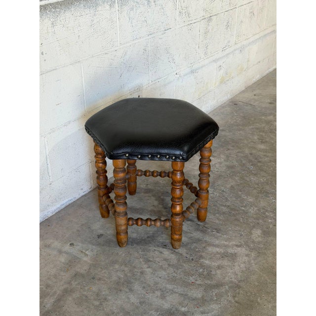 This striking hexagonal ottoman features a prominent nailhead trim bordering its upholstered top. Elaborately turned...