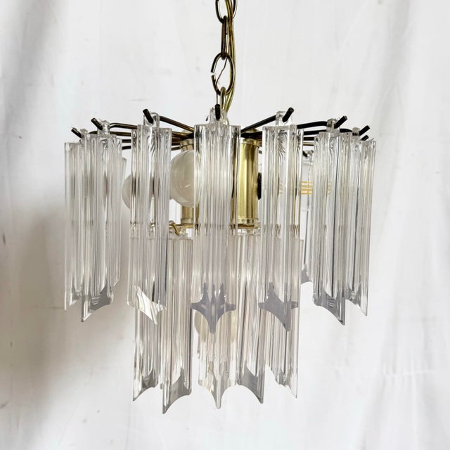 Striking Art Deco hanging chandelier featuring tiered lucite panels suspended around a warm brass-toned frame. The faceted...