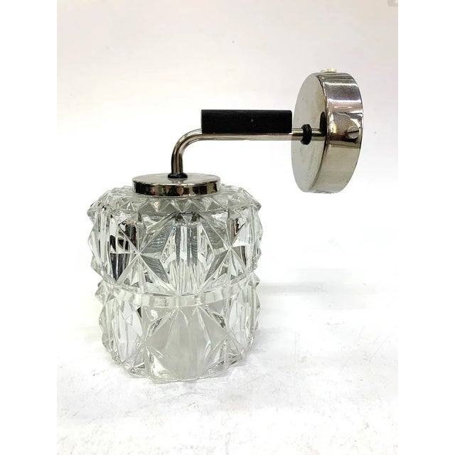 Chiseled glass wall light with nickel plated and wooden accents, 1970s. European Plug (up to 250V).The wiring of this item...